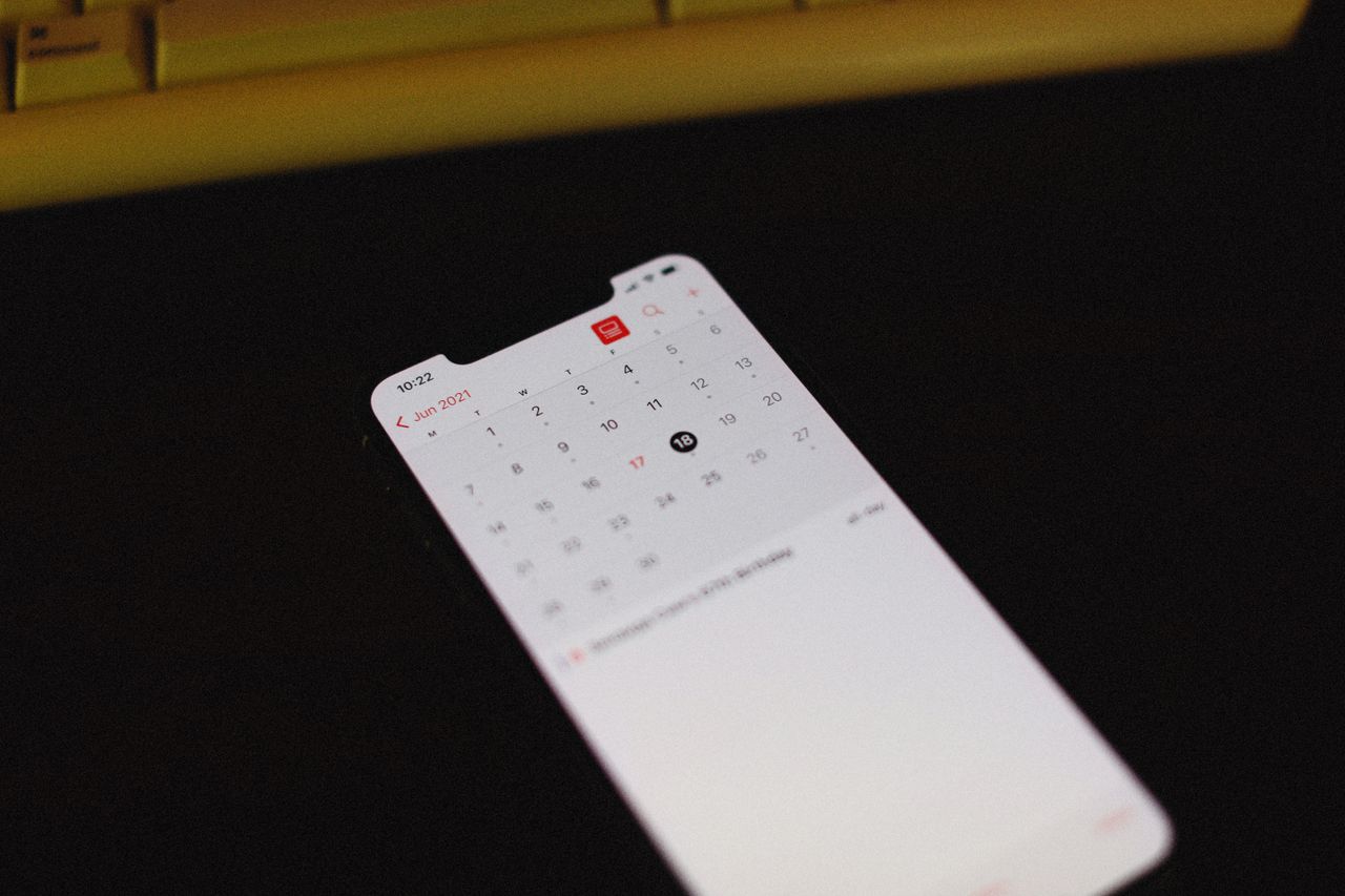 Smartphone with illuminated calendar app screen on a dark background, June 2021 visible.